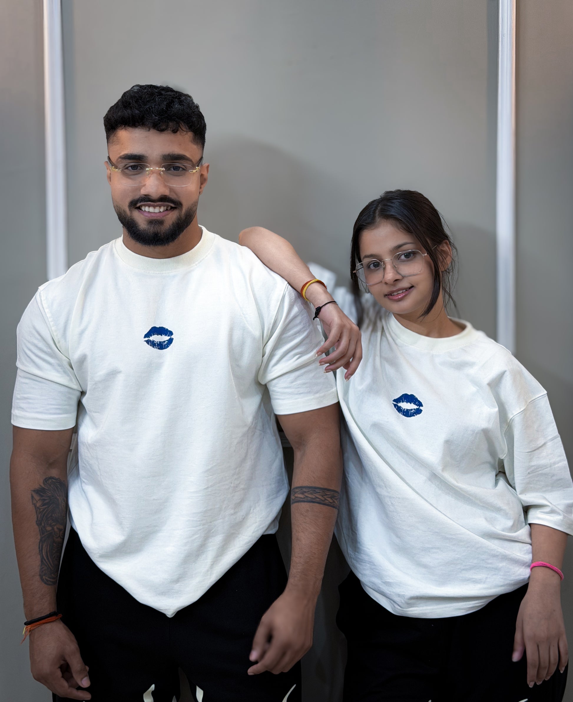 Two people wearing white t-shirts with a blue logo against a plain background