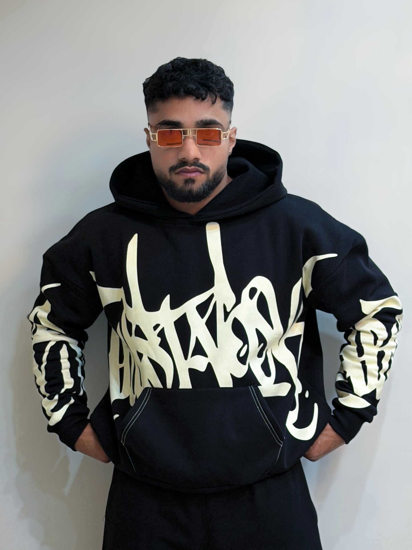 Person wearing a black hoodie with white text design against a plain background