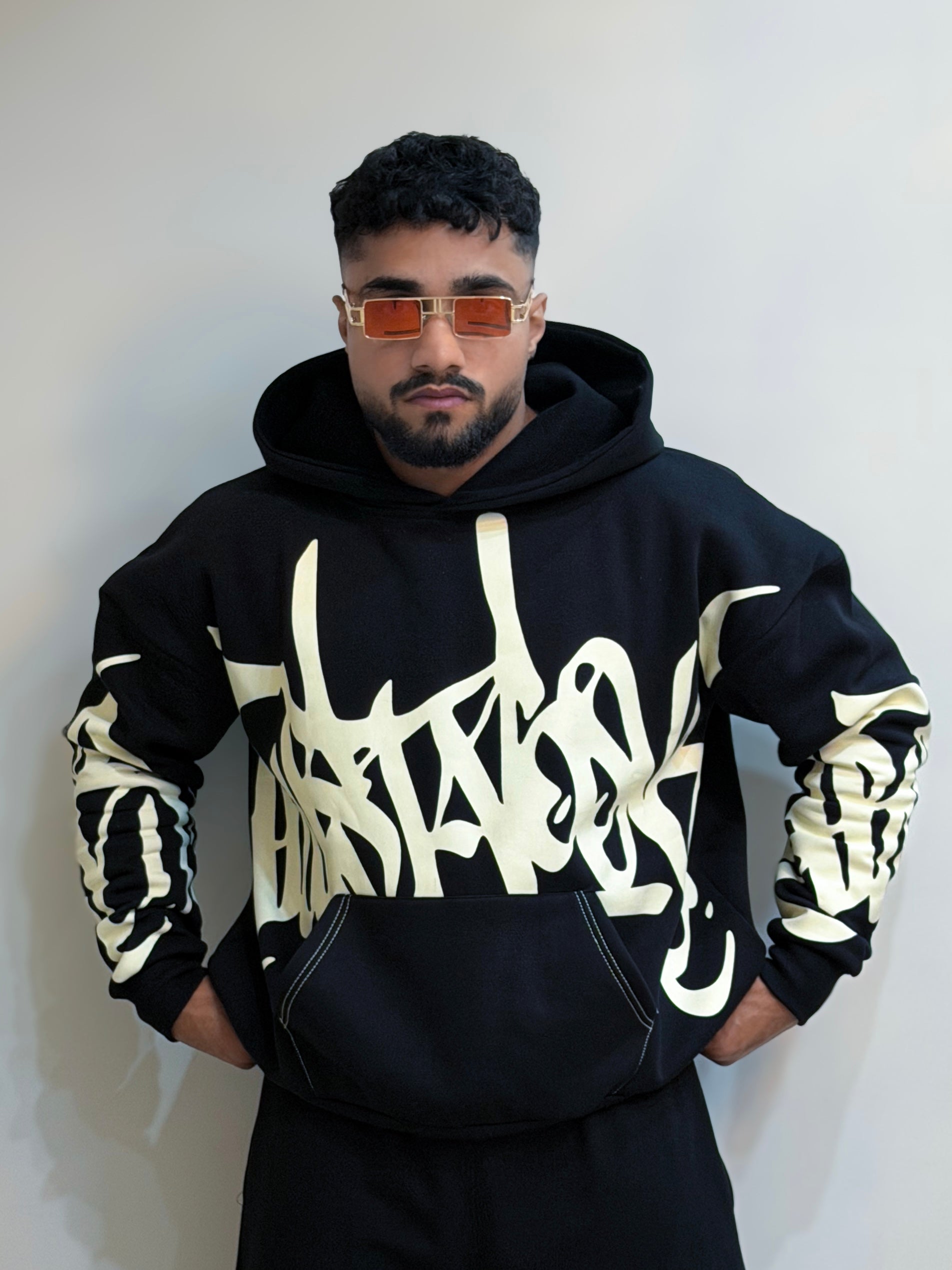 Person wearing a black hoodie with white text design against a plain background
