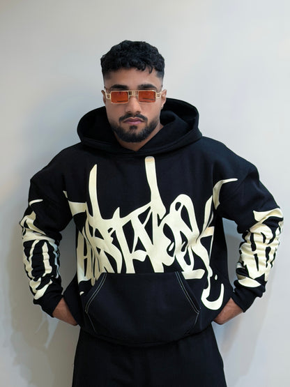 Person wearing a black hoodie with white text design against a plain background