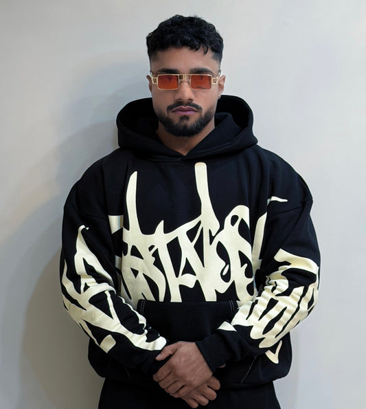 Man wearing a black hoodie with white text design against a plain background