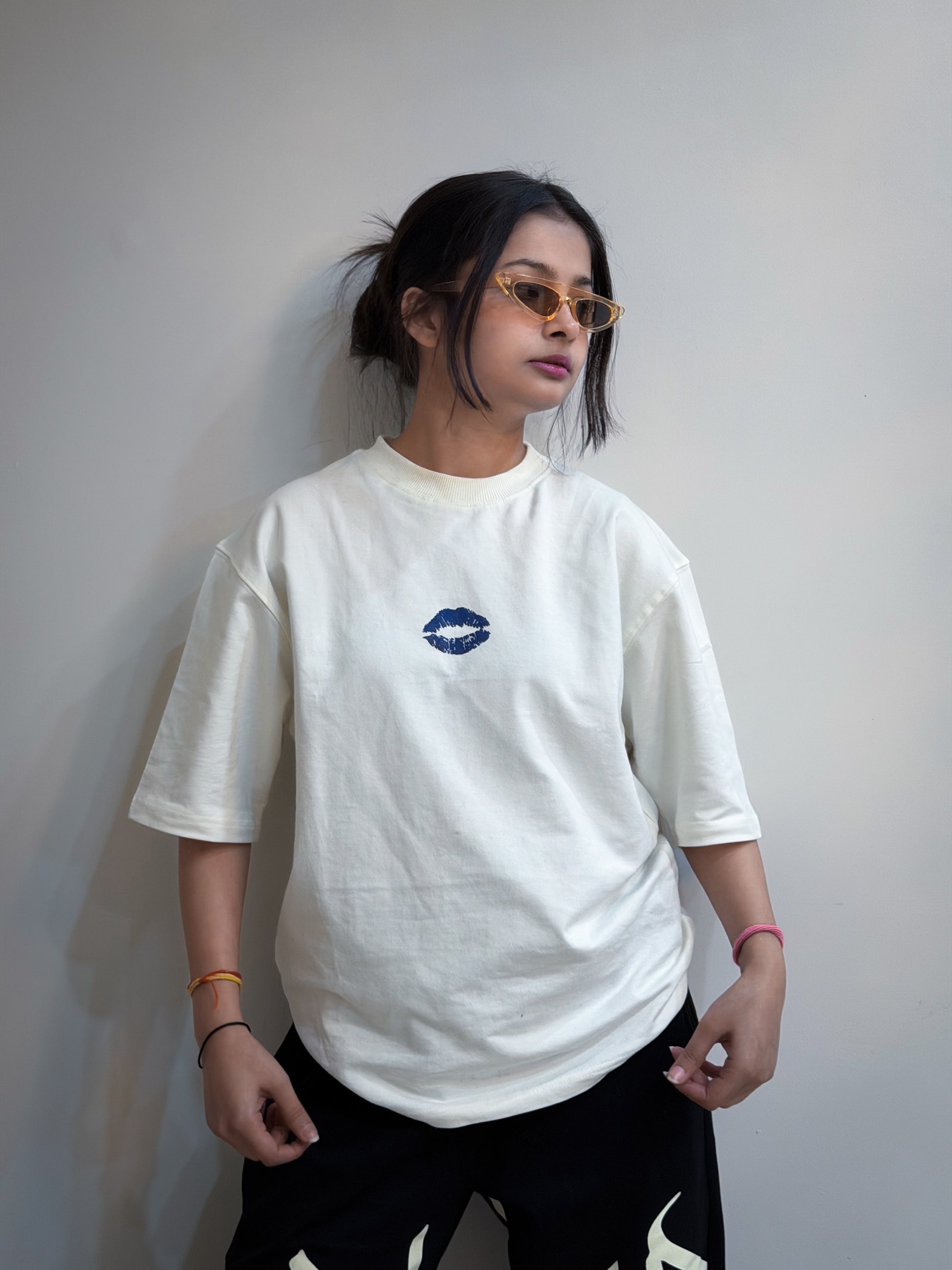 Person wearing a white t-shirt with a blue logo against a plain background