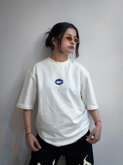 Person wearing a white t-shirt with a blue logo against a plain background