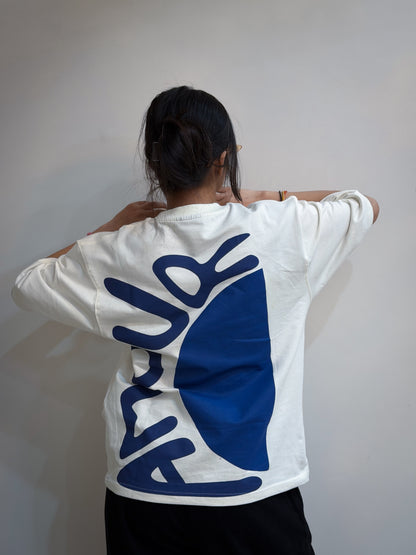 Person wearing a white sweatshirt with blue logo on the back against a plain background
