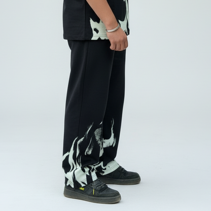 Person wearing black pants with white abstract designs on a white background