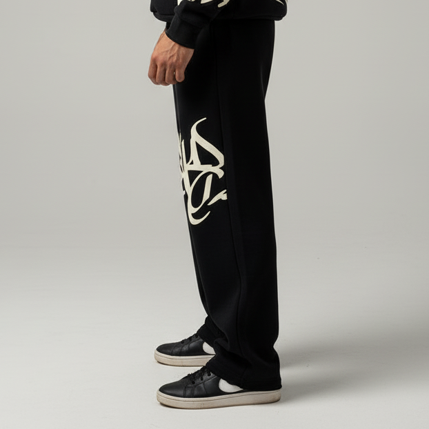 Black pants with a white logo worn by a person on a gray background