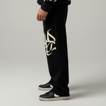 Black pants with a white logo worn by a person on a gray background